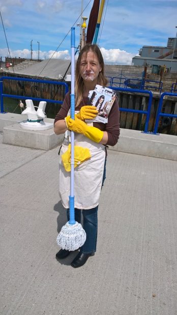 a-volunteer-dressed-up-as-a-domestic-servant-holding-a-mop